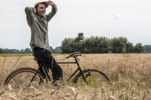 un uomo con la sua bicicletta in mezzo ad un campo di grano