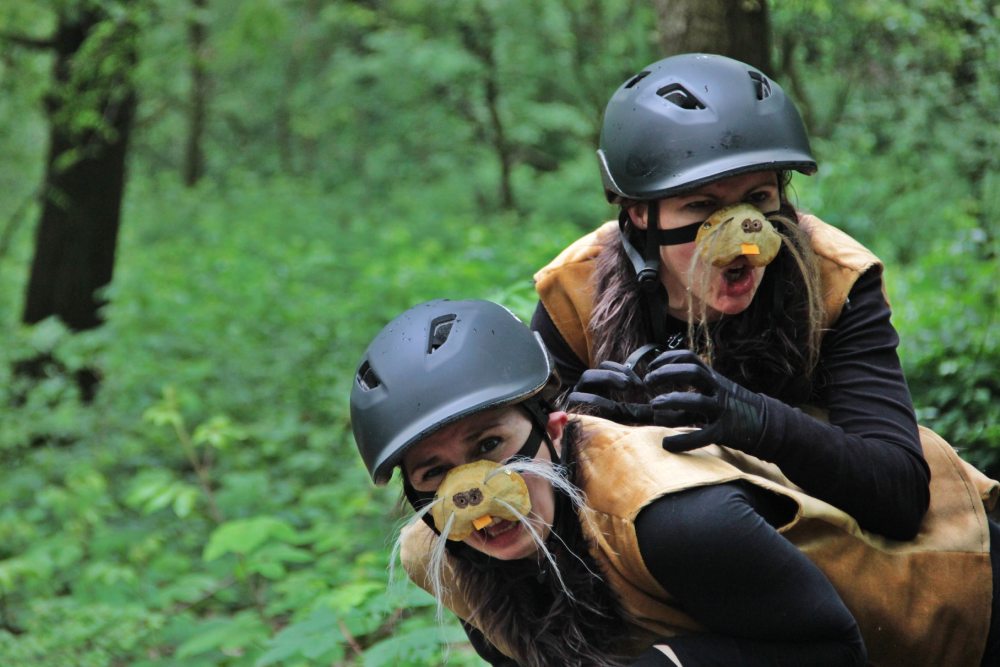 due attrici che interpretano delle nutrie con caschi da bici, una sopra l'altra